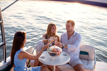 Friends on a boat in sunset drinking wine