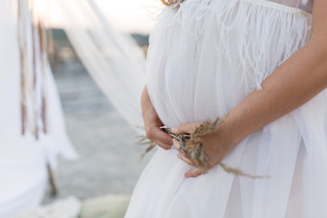 Obraz premium the pregnant woman keeps her hands on her stomach. pregnant woman in a dressing gown made of tulle. pregnant belly