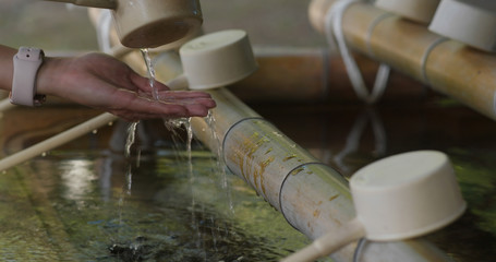 Woman wash hand before enter Japanese temple