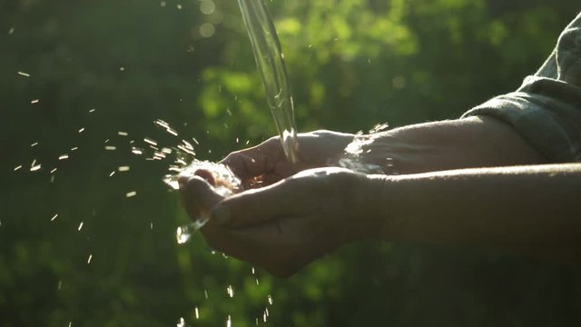 Water pouring in ederly farmer's hand, nature background, environment issues. Aqua pouring splash in hand. (Drought / Scarcity). Lack of fresh drinking water resources, water usage. Hands water splash