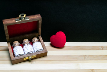 Old wooden box with homeopathic glass bottles of pills and heart on wood surface and dark background- Homeopathy for heart Concept