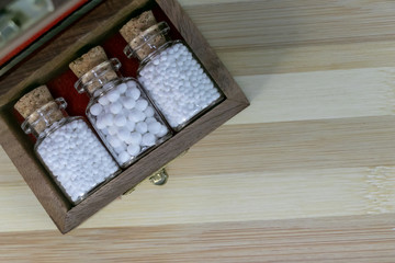 Old wooden box with Homeopathy pills in vintage bottles on wood background