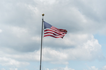 Lone stars and stripes on the flag of America waving in against a cloudy sky in summer.