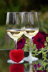 The photo shows glasses of white wine, a wedding gift, and flowers.