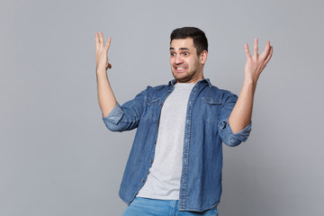 Angry mad sad upset unshaven young man in denim jeans shirt posing isolated on grey wall background...