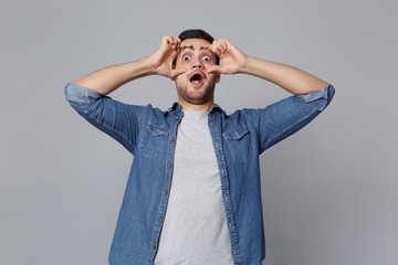 Handsome stylish unshaven young man in denim jeans shirt posing isolated on grey wall background...