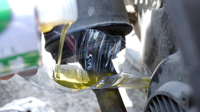 Pouring motor oil into motorcycle tank through piece of plastic bottle, lifehack