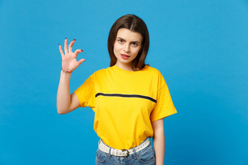 Portrait of concerned young woman in vivid casual clothes looking camera, gesturing demonstrating size with workspace isolated on bright blue background. People lifestyle concept. Mock up copy space.