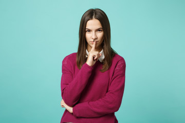 Young brunette woman girl in casual clothes posing isolated on blue green background studio portrait. People lifestyle concept. Mock up copy space. say hush be quiet with finger on lips shhh gesture.