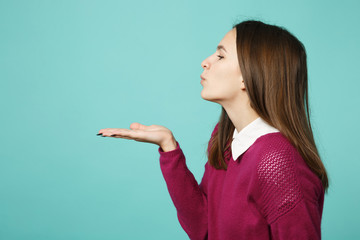 Side view of young brunette woman girl in casual clothes posing isolated on blue turquoise background studio portrait. People sincere emotions lifestyle concept. Mock up hold on hand palm copy space.