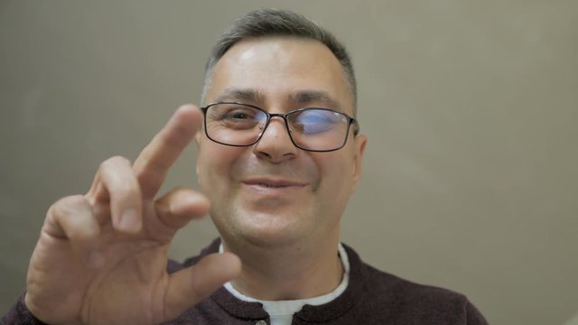 Close-up of a middle-aged man who bends down and talks tenderly, gesturing with his hands. Concept: a man communicates with a child.