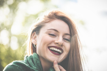 Eine junge Frau mit Schal, bzw. Kopftuch über den langen Haaren genießt im Garten die warme Sonne...