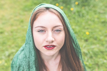 Eine junge Frau mit Schal, bzw. Kopftuch über den langen Haaren genießt im Garten die warme Sonne...