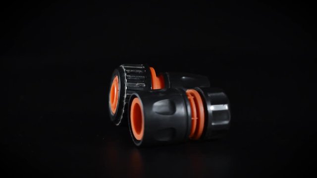 black with orange couplings for connecting plumbing hose on a black background