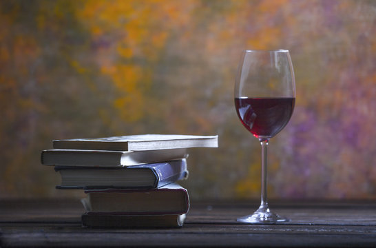 A pile of books and a glass of red wine