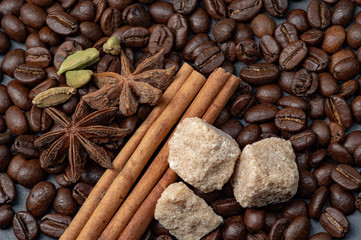 Composition of coffee and cane sugar on a stone background with the addition of anise, cinnamon and cane sugar.
