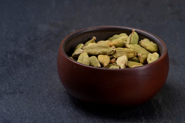Cardamom in ceramic cup on stone background. Close-up.