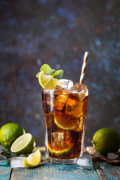 Fresh made Cuba Libre with brown rum, cola, mint and lemon on wooden background
