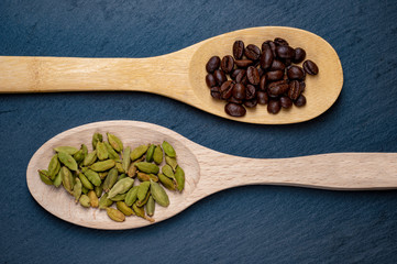 Coffee and cardamom on wooden spoons. Stone background