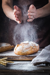Bäcker, der Brot kocht. Mann klatscht Mehl über den Teig. Männerhände beim Brotbacken