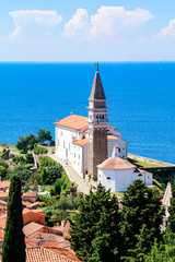 View of St George's Church and the red tiled rooftops of the old town of Piran in Slovenia, with the Adriatic Sea in the background