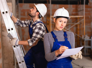 Female foreman checking the work of the builders in house