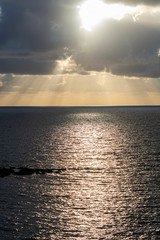 Fototapeta na wymiar Dramatic sunset over sea water with gray clouds and sun lights