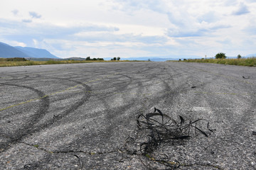 Pieces of car tires on asphalt surface with skid tracks. Marks of drifting cars on racetrack surface. Former runway near Sapareva Banya, Bulgaria, now used for car races
