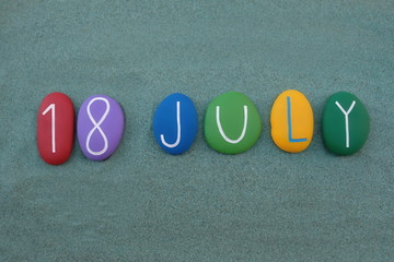 18 July, calendar date composed with multi colored stones over green sand