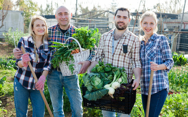 Obraz premium Happy farmers posing with a harvest of vegetables