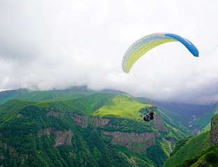 Tandem paragliding, green mountain valley on a cloudy day. Caucasus, Georgia 