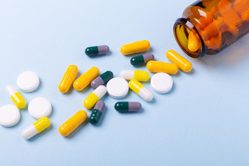 Multicolor tablets and pills capsules from glass bottle on blue background Heap of assorted various medicine tablets and pills. Health care Close-up Copy space