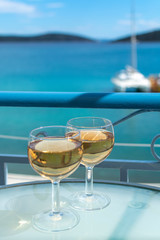 White wine served outside on balcony on glass table with sea view