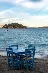 Traditional greek tavern with wooden tables on sandy beach near water waiting for tourists in Tolo, Peloponnese, Greece