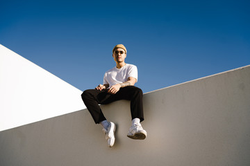 Young man wearing knit hat sitting on wall