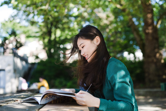 Young woman reading magazine in park