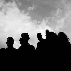 A black and white silhouette of a group of people with sky in the background