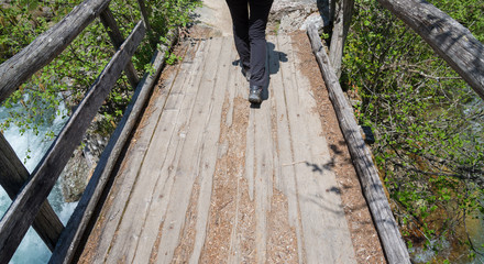 Naklejka premium Walking on a wooden bridge over a little stream, italian alps, Italy