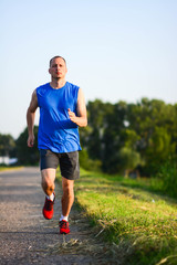 Athletic young man running in the nature. Healthy lifestyle. sunlighte, sunrise, golden-hour. Portrait, Vertical.