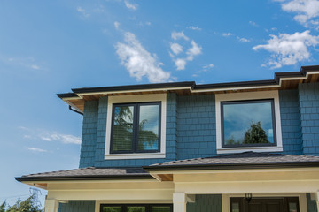 The top of the house with nice windows on cloudy sky background