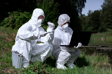 Ecological problem. Pollution. Examine oxygen. Scientist in protective mask and suit taking water samples from river. Chemist makes an analysis of the environment for radiation. Saving planet earth.