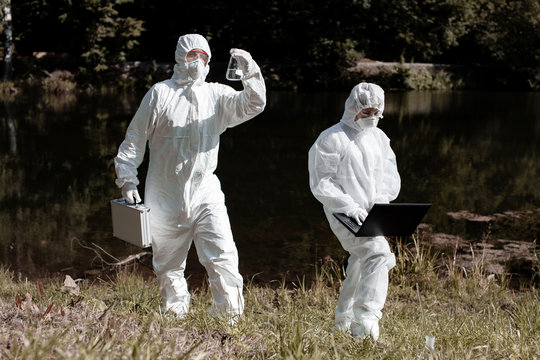 Ecological problem. Pollution. Examine oxygen. Scientist in protective mask and suit taking water samples from river. Chemist makes an analysis of the environment for radiation. Saving planet earth.