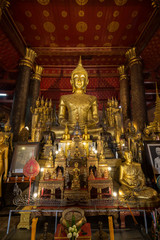 Altar with many golden Buddha statues at the Wat May Souvannapoumaram (Suwannaphumaham) (or Wat Mai, Wat May), a Buddhist temple, in Luang Prabang, Laos.