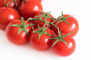 Branch of a fresh red tomato cherry, isolated on a white background close up corner composition