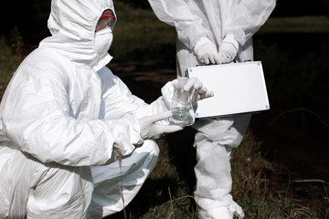 Ecological problem. Pollution. Examine oxygen. Scientist in protective mask and suit taking water samples from river. Chemist makes an analysis of the environment for radiation. Saving planet earth.