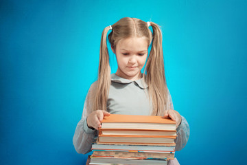 Child schoolgirl reading a book on blue background