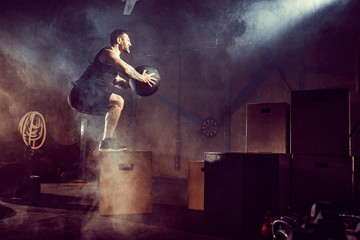 Athlete gave exercise. Jumping on the box. Phase touchdown. Gym shots in the dark tone. Smoke in gym.