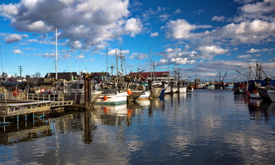 Fototapeta na wymiar Fishing Boats in Marina and a cloudy sky. This marina is located in the Steveston area of Richmond. The fishing village formed in this place was the first settlement on the territory of Richmond 