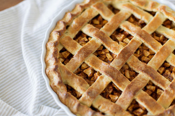 food, culinary and cooking concept - close up of apple pie in baking mold on kithchen towel