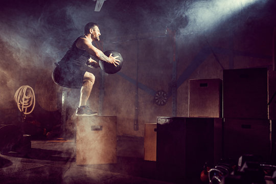 Athlete gave exercise. Jumping on the box. Phase touchdown. Gym shots in the dark tone. Smoke in gym.